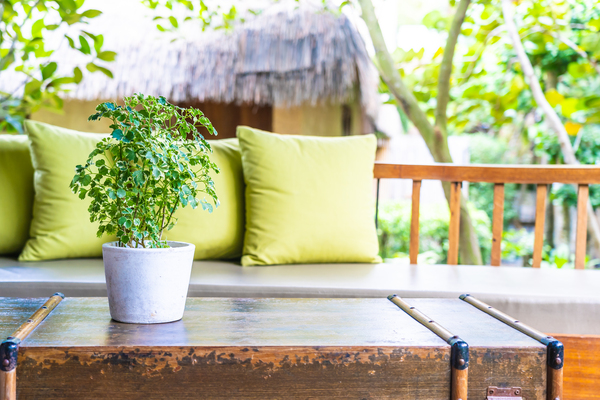 Couch mit grünen Kissen und Tisch auf Balkon